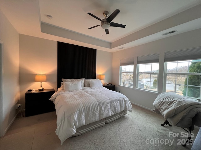 bedroom featuring a raised ceiling, ceiling fan, and carpet flooring