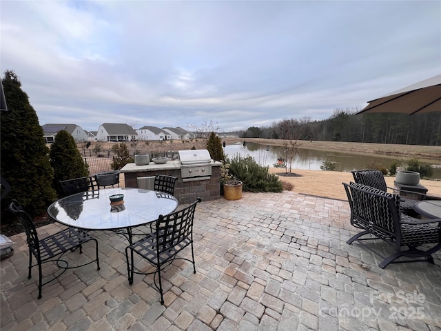 view of patio / terrace featuring a water view, an outdoor kitchen, and area for grilling