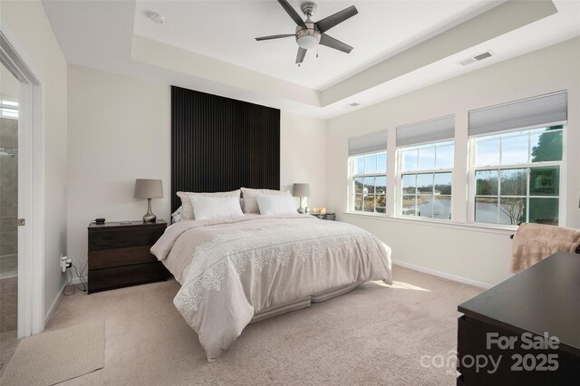 carpeted bedroom featuring a tray ceiling and ceiling fan