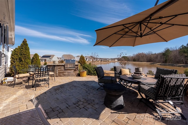 view of patio featuring grilling area, an outdoor kitchen, and a water view