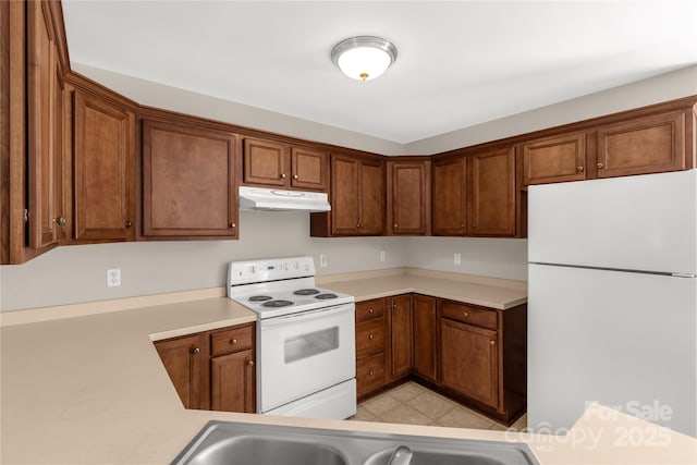 kitchen with brown cabinets, white appliances, light countertops, and under cabinet range hood