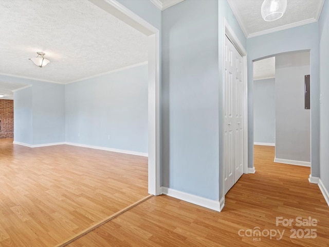 hall with ornamental molding, wood-type flooring, and a textured ceiling