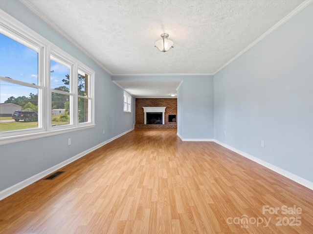 unfurnished living room with crown molding, a fireplace, light hardwood / wood-style floors, and a textured ceiling