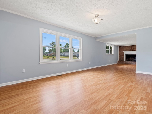 unfurnished living room with crown molding, a fireplace, light hardwood / wood-style floors, and a textured ceiling