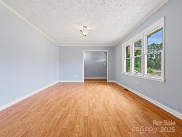 spare room with crown molding, a textured ceiling, and light wood-type flooring