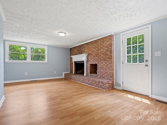 unfurnished living room featuring a brick fireplace, a textured ceiling, light hardwood / wood-style flooring, and a healthy amount of sunlight