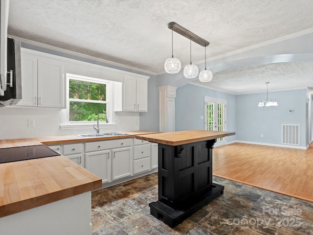 kitchen with wood counters, decorative light fixtures, sink, and white cabinets