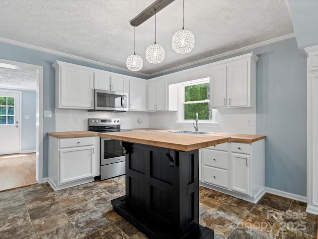 kitchen featuring appliances with stainless steel finishes, pendant lighting, white cabinetry, butcher block counters, and sink