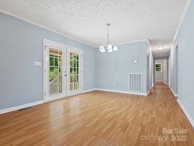 empty room with crown molding, a textured ceiling, light hardwood / wood-style floors, and french doors