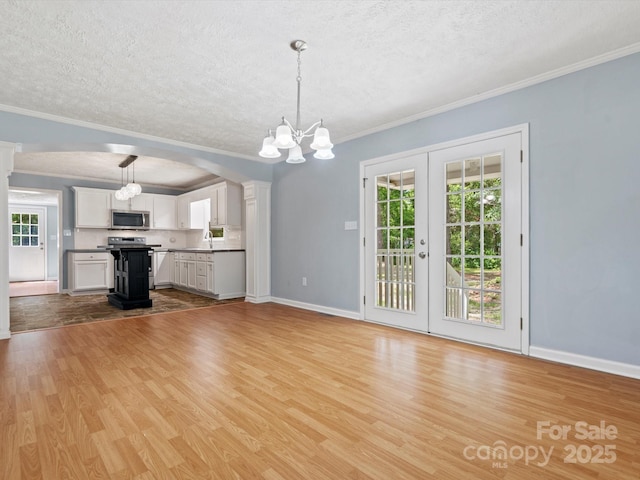 unfurnished living room with plenty of natural light, a textured ceiling, and light wood-type flooring