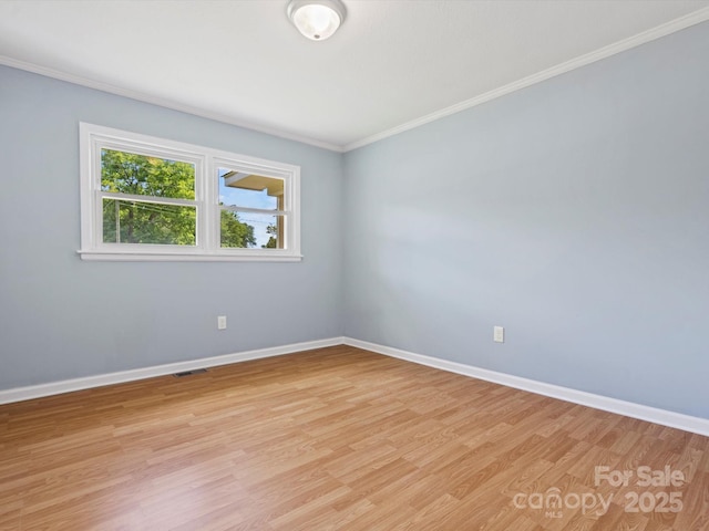 spare room with ornamental molding and light wood-type flooring