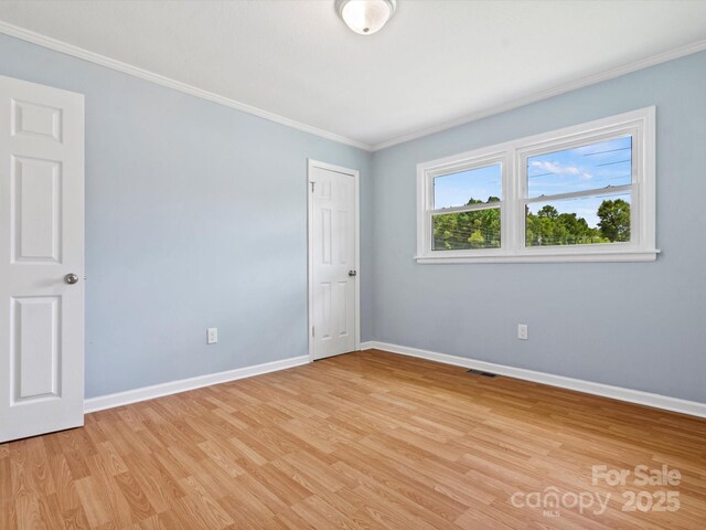 spare room featuring ornamental molding and light wood-type flooring