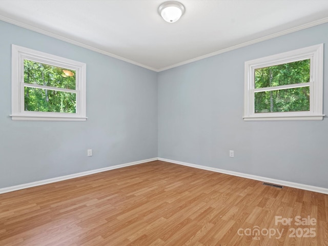 empty room with crown molding, a healthy amount of sunlight, and light hardwood / wood-style flooring