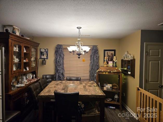 dining area featuring a textured ceiling, dark hardwood / wood-style floors, and a chandelier