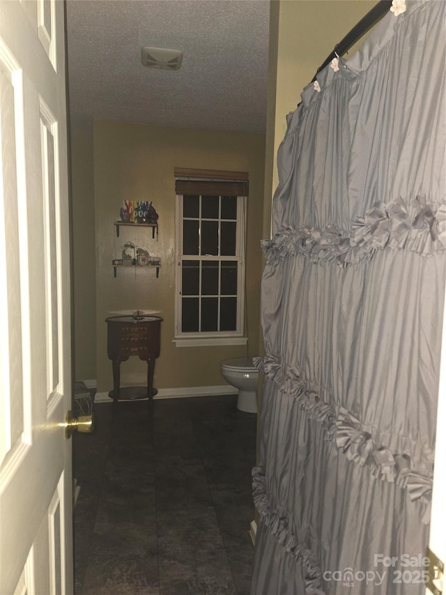 bathroom with toilet and a textured ceiling