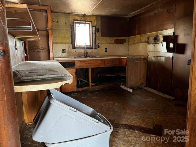 kitchen featuring brown cabinets, light countertops, and a sink