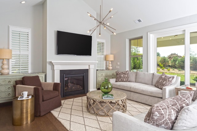 living room with high vaulted ceiling, a chandelier, and light hardwood / wood-style floors