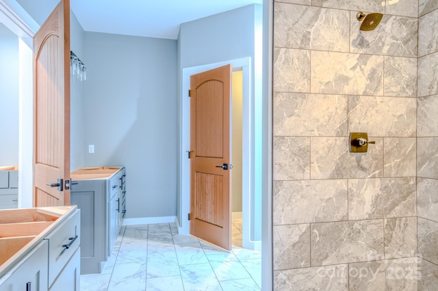 bathroom with a tile shower and vanity