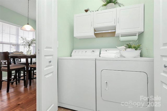 washroom featuring cabinets, hardwood / wood-style floors, and independent washer and dryer