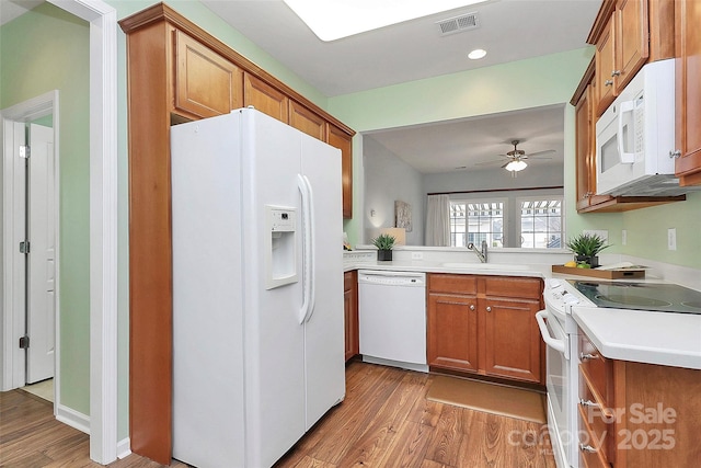 kitchen featuring ceiling fan, sink, white appliances, and light hardwood / wood-style flooring