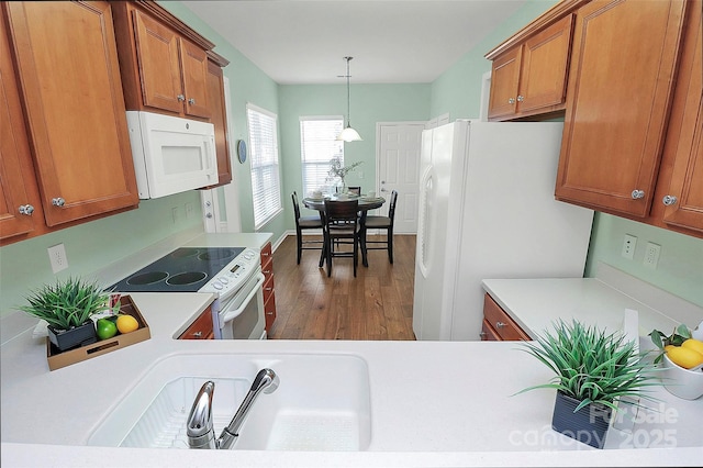 kitchen with white appliances, dark wood-type flooring, and decorative light fixtures