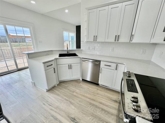 kitchen with stainless steel appliances, sink, white cabinets, and kitchen peninsula