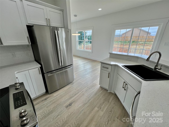 kitchen featuring stainless steel refrigerator, white cabinetry, sink, decorative backsplash, and light hardwood / wood-style flooring