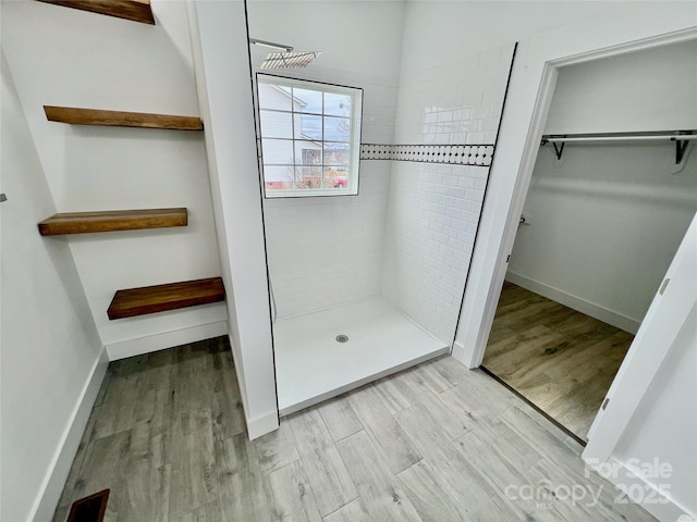 bathroom featuring wood-type flooring and a tile shower