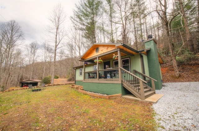 rear view of house featuring a yard and covered porch