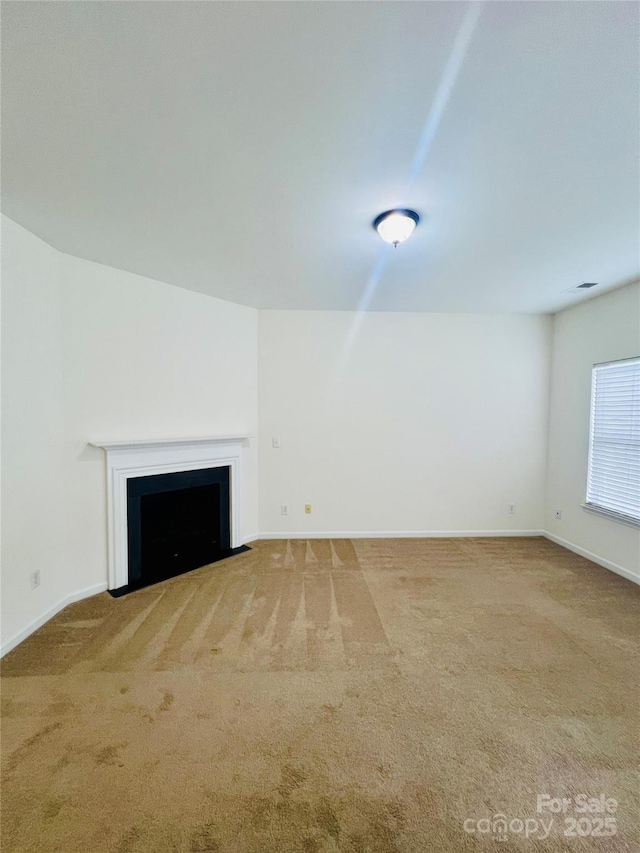 unfurnished living room featuring carpet floors, baseboards, and a fireplace with flush hearth