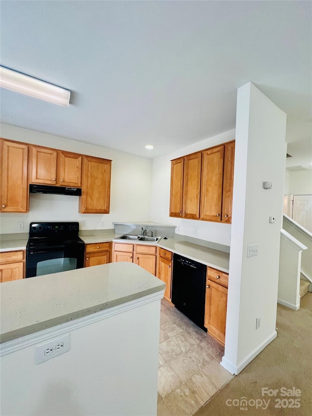 kitchen with brown cabinetry, a sink, black appliances, under cabinet range hood, and baseboards