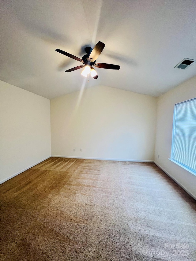 carpeted spare room featuring lofted ceiling, ceiling fan, visible vents, and baseboards