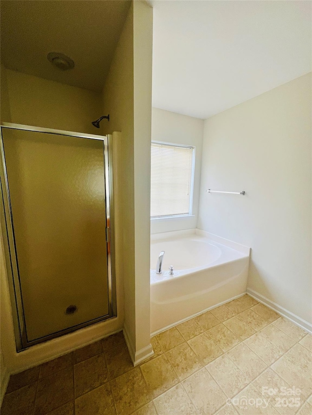 full bathroom featuring a garden tub, a shower stall, baseboards, and tile patterned flooring