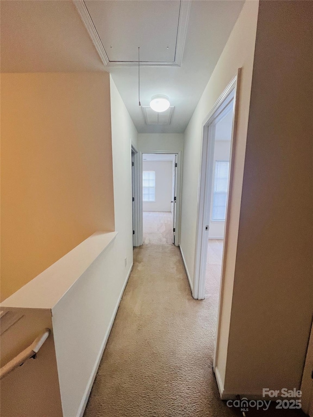 hall with baseboards, an upstairs landing, attic access, and light colored carpet