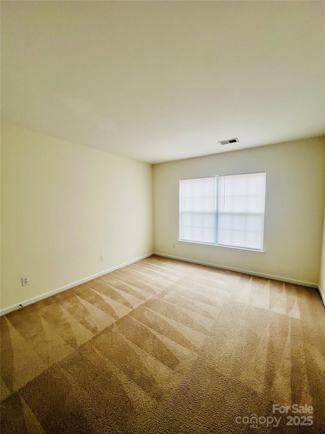 carpeted empty room featuring baseboards and visible vents