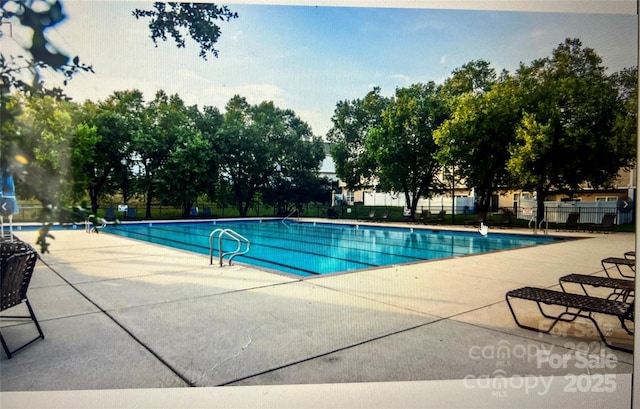 community pool with fence and a patio