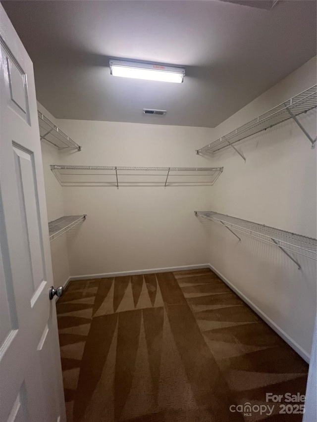 walk in closet featuring dark colored carpet and visible vents