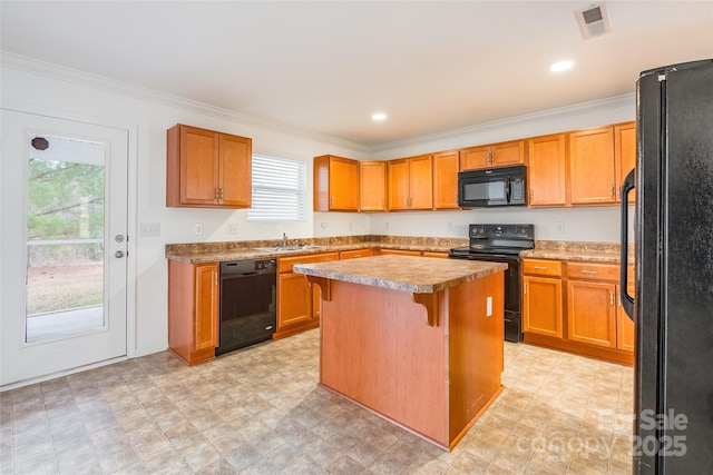 kitchen featuring sink, a breakfast bar area, ornamental molding, a kitchen island, and black appliances