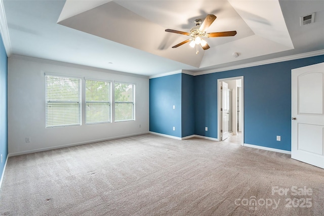 empty room with ornamental molding, light colored carpet, ceiling fan, and a tray ceiling