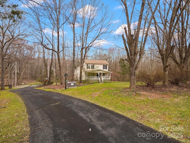 view of front of property with covered porch, aphalt driveway, and a front yard