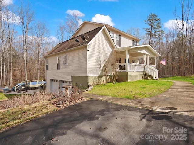 view of home's exterior with a porch, a lawn, driveway, and an attached garage