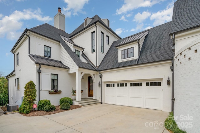 view of front of home with a shingled roof, concrete driveway, an attached garage, a standing seam roof, and metal roof