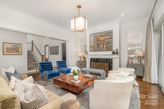 living room featuring stairs, a high end fireplace, crown molding, and wood finished floors