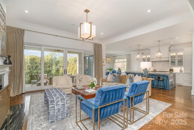 living area featuring french doors, ornamental molding, dark wood finished floors, and a notable chandelier