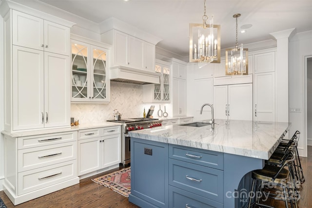 kitchen featuring stainless steel stove, a sink, white cabinetry, custom exhaust hood, and crown molding