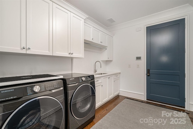 clothes washing area with cabinet space, dark wood-type flooring, a sink, separate washer and dryer, and baseboards