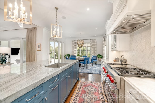 1328 S Kings Dr, Charlotte, NC 28207 - kitchen featuring a chandelier, range with two ovens, premium range hood, a sink, and blue cabinets