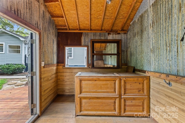 interior space featuring light hardwood / wood-style flooring, vaulted ceiling, wooden ceiling, and wood walls