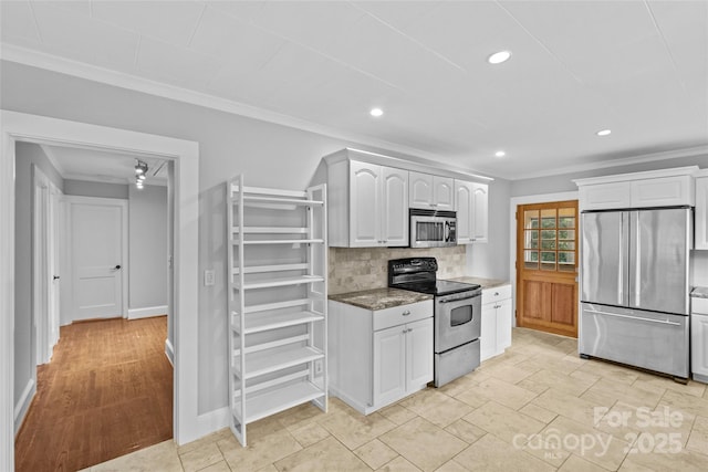 kitchen featuring appliances with stainless steel finishes, white cabinetry, backsplash, dark stone counters, and ornamental molding