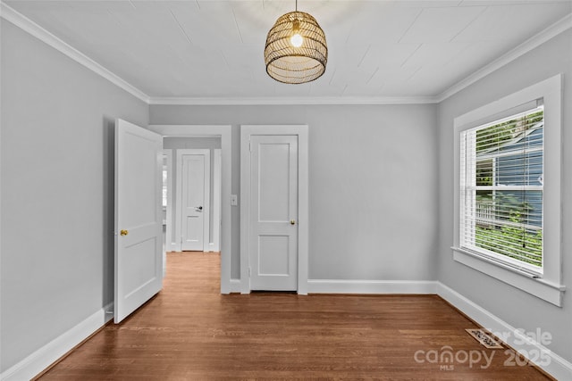 empty room with ornamental molding and hardwood / wood-style floors